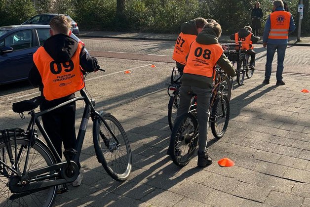 Leerlingen stappen op hun fiets voor het praktijkexamen.